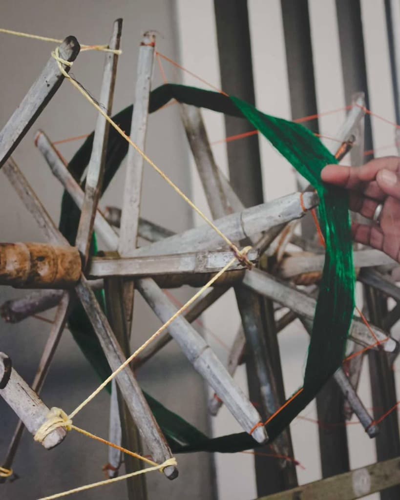 Traditional bamboo swift wheel winding rich emerald-green dyed handloom silk yarn for designer capsules